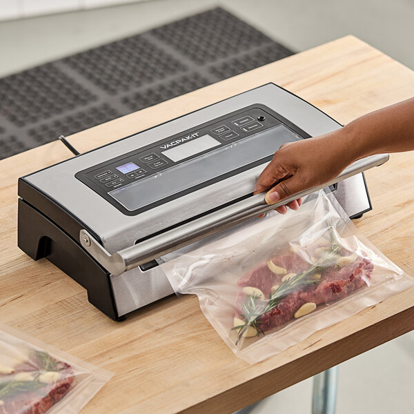 VacPak-It vacuum sealer in a professional kitchen sealing a plastic bag of meat.