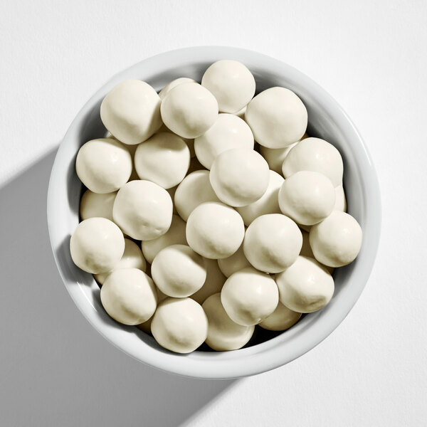 A bowl filled with round, white yogurt-covered pretzel balls.