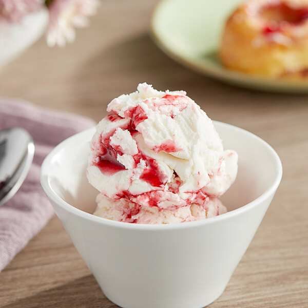 A bowl of ice cream with red raspberry sauce.