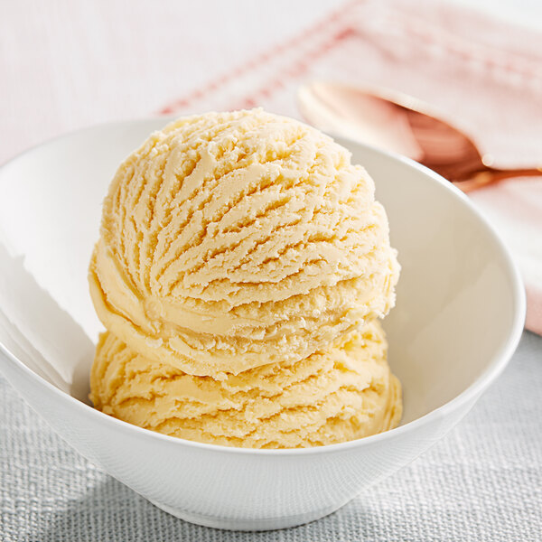 A bowl of mango hard serve ice cream with a spoon in it.