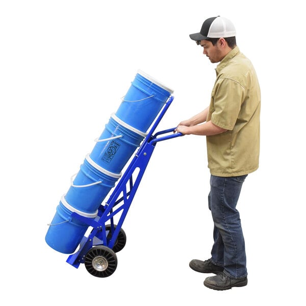 A man using a Vestil steel pail hand truck to move a blue steel pail.