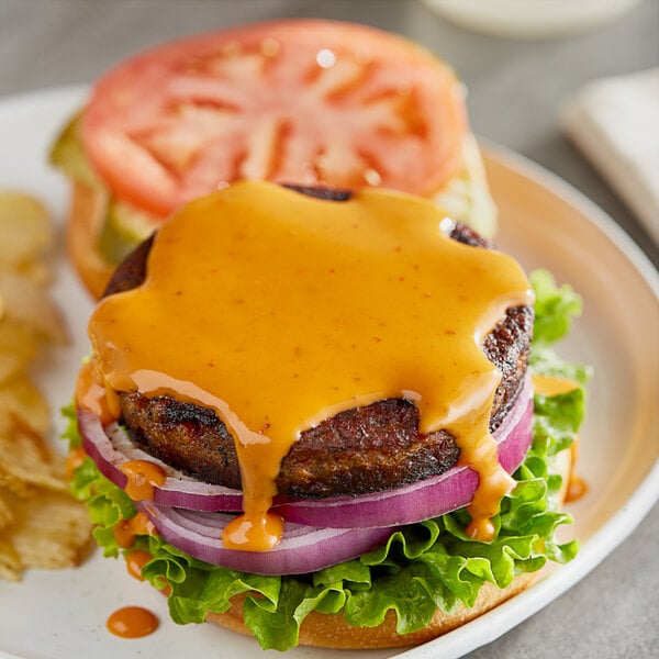 A burger with lettuce, cheese, and tomato with a side of potato chips on a plate.