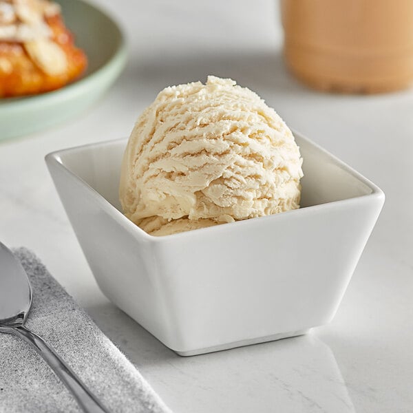 A bowl of I. Rice Butter Pecan Hard Serve Ice Cream with a spoon in it.