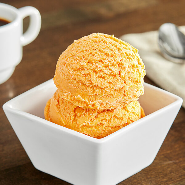 A bowl of orange pumpkin ice cream on a table.