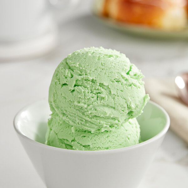 A bowl of I. Rice green apple hard serve ice cream with a spoon.