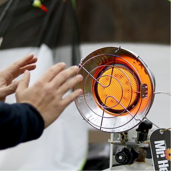 A person touching a Mr. Heater single burner liquid propane tank top heater.