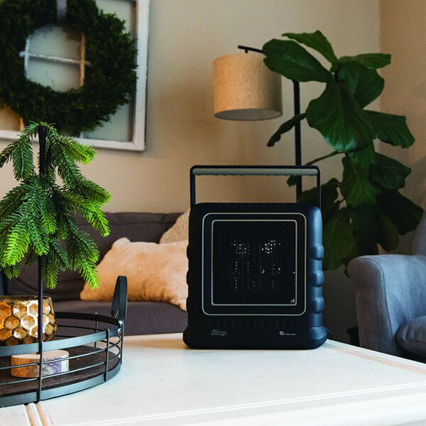 A black Mr. Heater Electric Buddy portable heater on a white table in a living room.