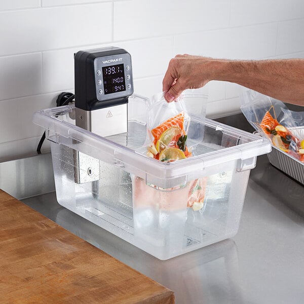 A person using a VacPak-It polycarbonate water bin to hold a bag of food.