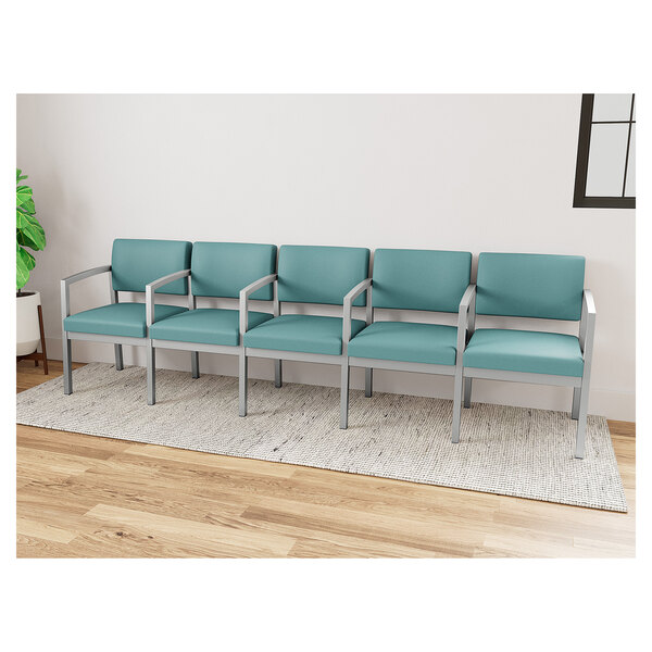 A row of blue Lesro Lenox Steel Patriot Plus vinyl chairs with silver armrests.