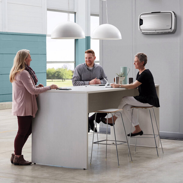 A group of people sitting at a table in a corporate office using a Fellowes AeraMax Pro air purifier.