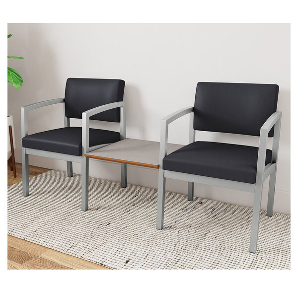 Two Lesro Lenox black chairs with armrests connected by a white table.