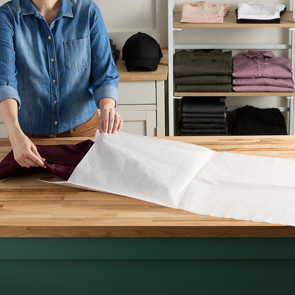 A person cutting white paper on a table.