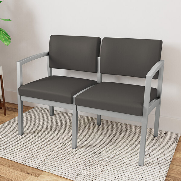 A Lesro Lenox steel and vinyl loveseat in front of a white wall.