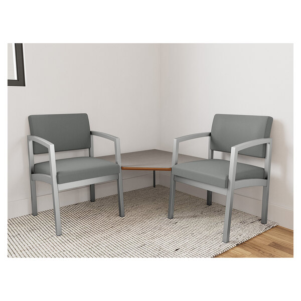 Two Lesro Lenox grey fabric arm chairs with a Sarum Twill laminate corner table in a lounge area.
