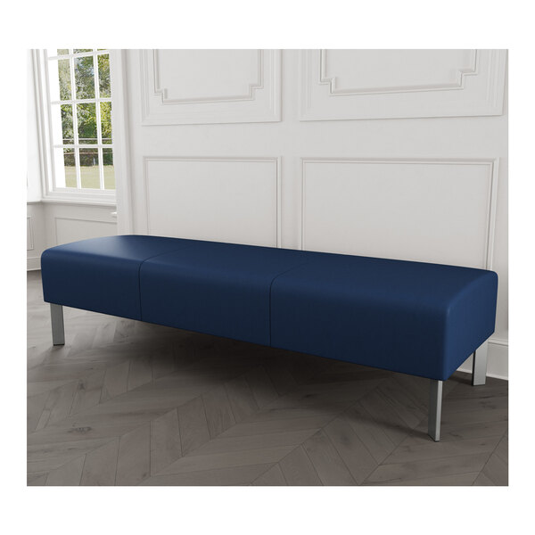 A Lesro Luxe Lounge blue vinyl bench with steel legs in a room with a white wall.