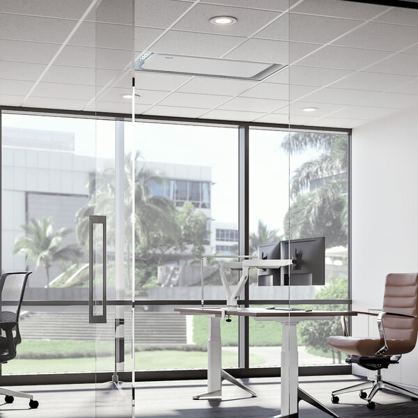 A white room with a Fellowes Array Recess AR1 ceiling-mounted air purifier above a desk and chairs.
