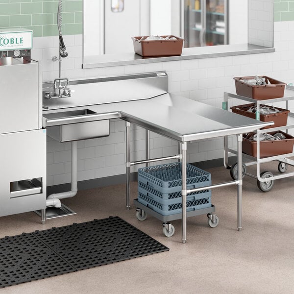 A Regency stainless steel L-shape dishtable on a counter in a professional kitchen with a sink.