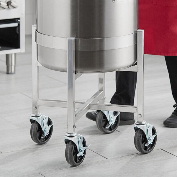 A man using a stainless steel stock pot dolly.