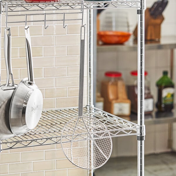 A white metal grid with a circle in the middle on a metal rack with pots and pans.