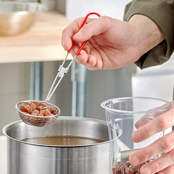 A person using a Choice boba scoop to pour brown boba into a plastic cup.