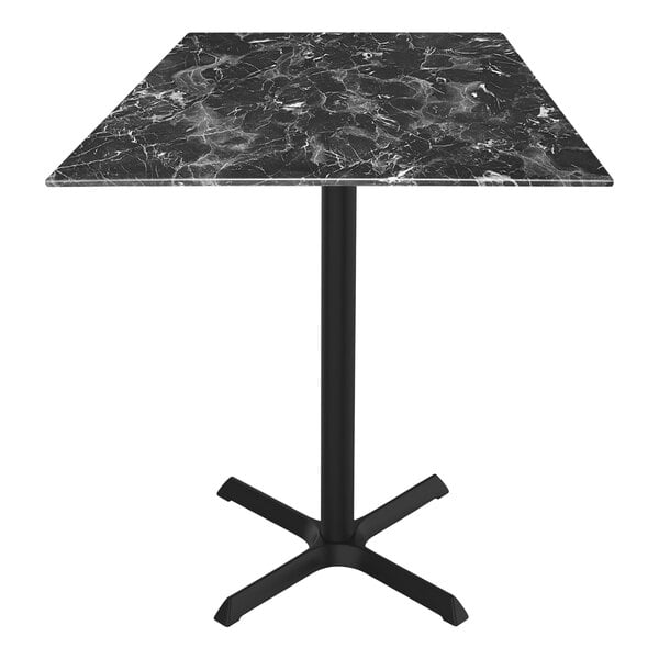 A Holland Bar Stool black marble table with metal cross base.