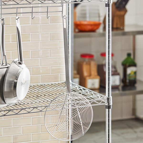 A metal rack with a Choice 9" Round Spiral Skimmer hanging on it.