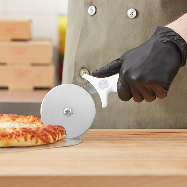 A person in black gloves using an American Metalcraft stainless steel pizza cutter to cut a pizza.