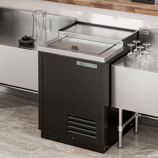 A black and silver refrigerated True glass froster on a metal counter.
