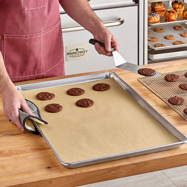 A person using a Baker's Lane parchment paper lined tray to bake cookies.