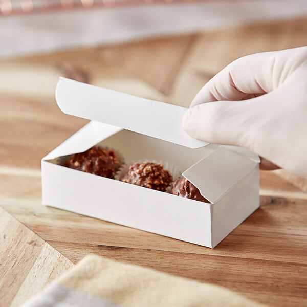 A hand holding a Baker's Lane white box of chocolate candies.