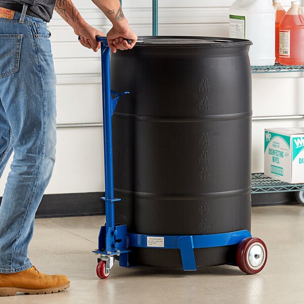 A man using a Lavex drum caddy to push a black barrel.