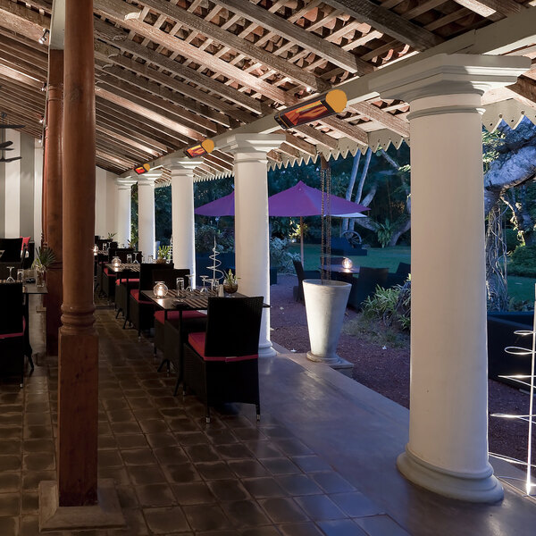 A Big Ass Fans black electric heater on a restaurant patio table with a red cushion.