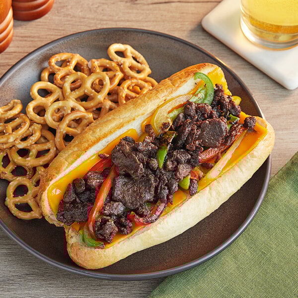 A plate with a sandwich made with PAOW! Plant-Based Beef and vegetables next to pretzels.