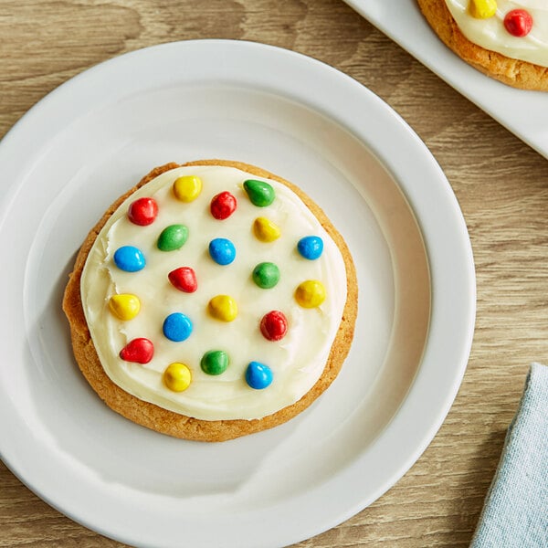 A close up of a cocoa drop with white icing and colorful sprinkles.