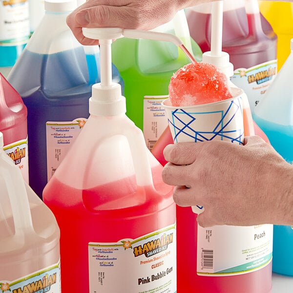 A hand pouring Hawaiian Shaved Ice Pink Bubble Gum Snow Cone Syrup into a cup.