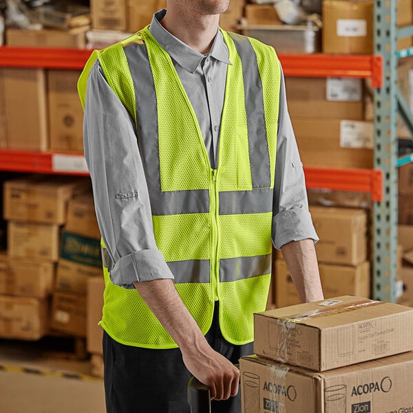 A man wearing a Lavex lime green high visibility safety vest standing in a warehouse.