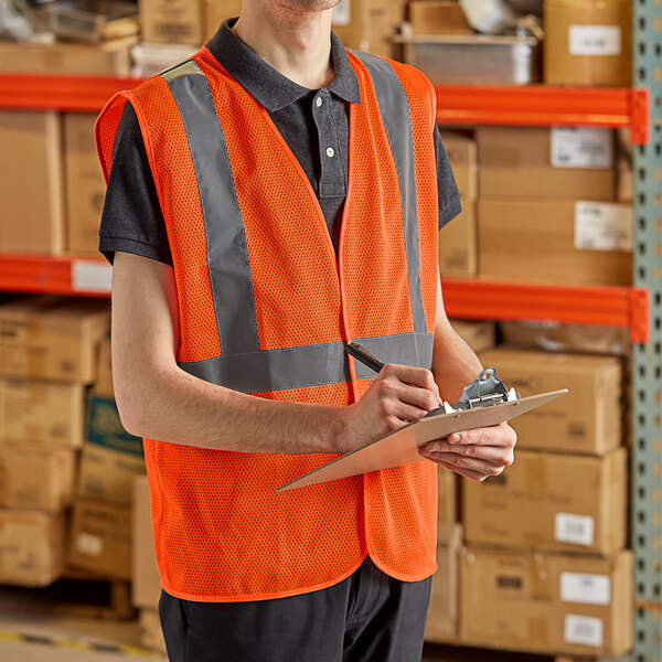 A man in a Lavex orange high visibility safety vest writing on a clipboard.