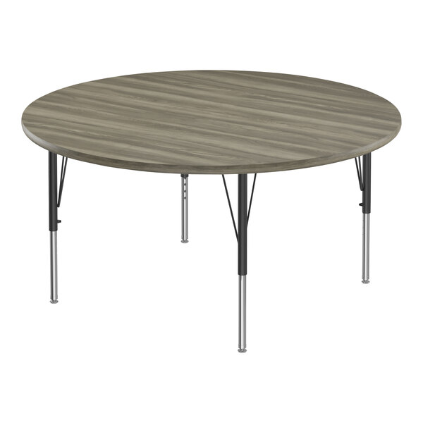 A Correll round activity table with black metal legs and a gray driftwood top with black trim.