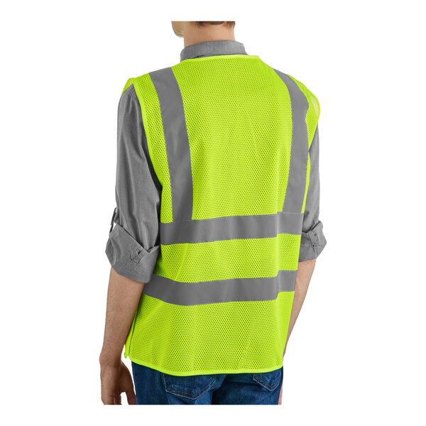 A person wearing a lime green high visibility safety vest with reflective stripes.