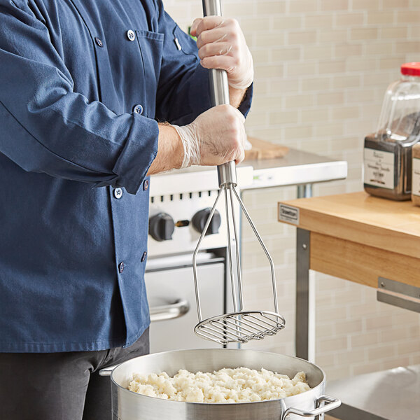 A person using a Fourt&#233; stainless steel round-faced potato masher in a pot of food.