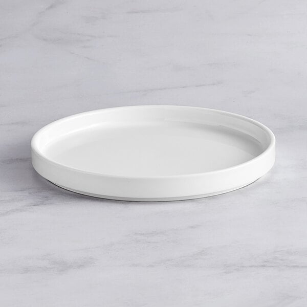 An Acopa Lore bright white porcelain plate on a marble surface.
