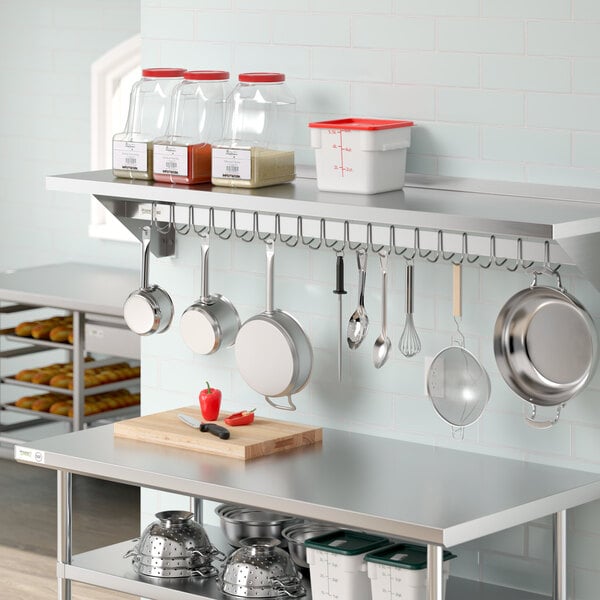 A kitchen with a Regency stainless steel wall-mounted pot rack holding pots and pans.