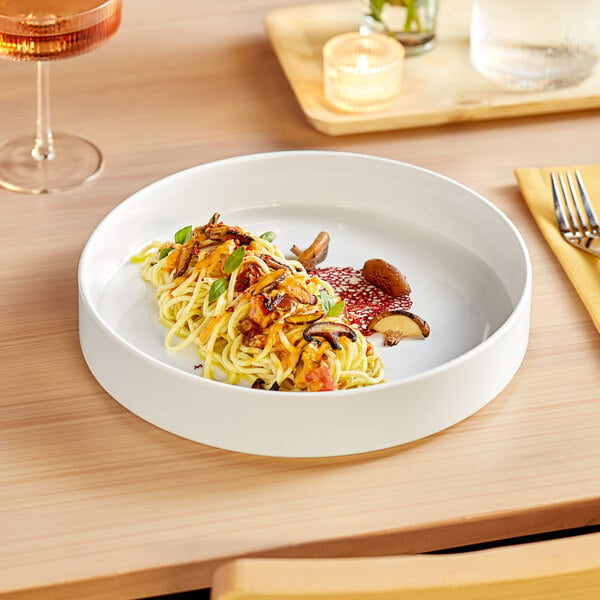 A white Acopa Lore porcelain deep plate with food on a table.