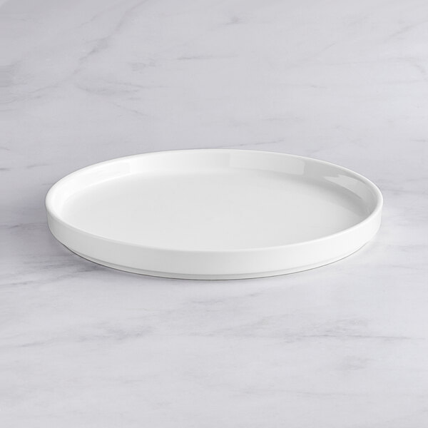 An Acopa Lore bright white porcelain plate on a marble surface.