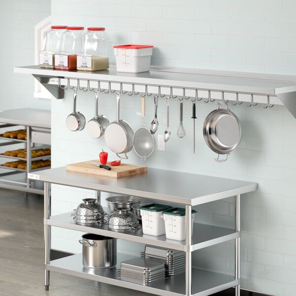 A kitchen with a Regency stainless steel wall-mounted pot rack shelf holding pots.