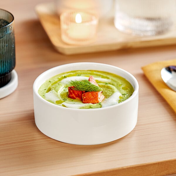 A white Acopa Lore porcelain bowl of soup on a table.