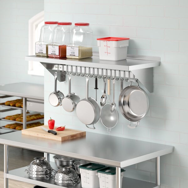 A kitchen with pots and pans hanging from a Regency stainless steel wall-mounted pot rack shelf.