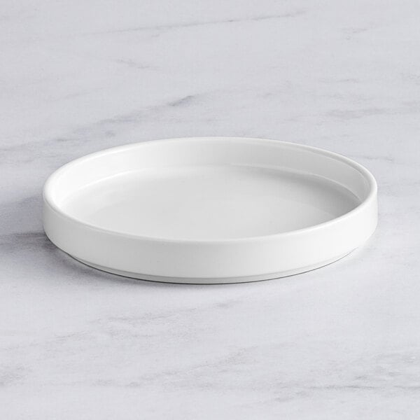 An Acopa Lore bright white porcelain plate on a marble surface.