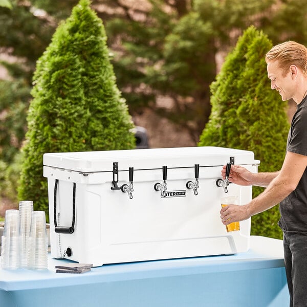 A man pouring beer from a tap on a CaterGator white insulated jockey box with four taps.