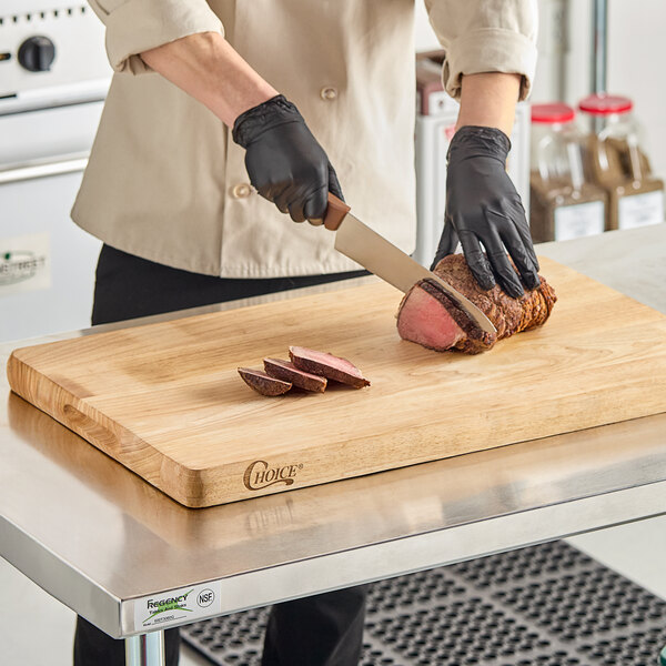 A person in gloves cutting meat on a Choice wood cutting board.